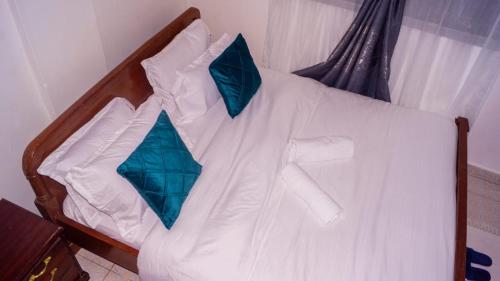 un letto con lenzuola bianche e cuscini blu di One Bed Garden Estate Nairobi a Nairobi