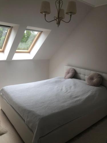 a white bedroom with a bed with two pillows at Zaciszny dom in Szczecin