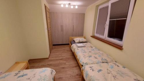 2 Betten in einem kleinen Zimmer mit Fenster in der Unterkunft Domki Całoroczne Południowy Stok in Gmina Gródek nad Dunajcem