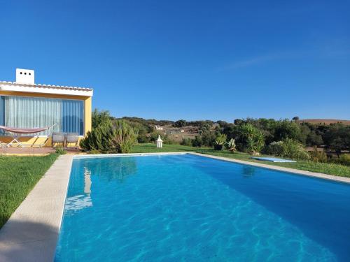 a blue swimming pool in front of a house at Casa dos Sobreiros in Cuba