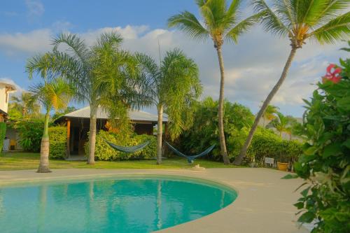 a resort with a hammock and palm trees at LES PECHEURS DU LAGON in Saint-Leu