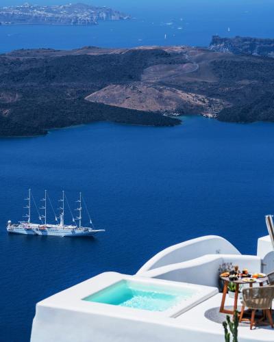a large boat in the water with a cruise ship at Eteoro Suites in Imerovigli