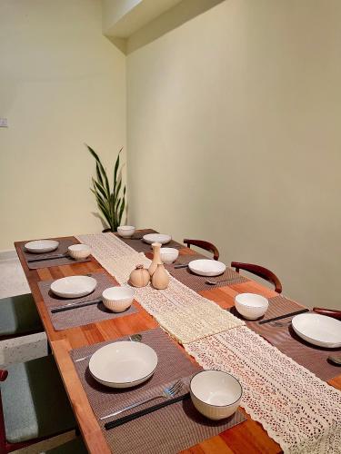 a wooden table with plates and utensils on it at V Lodge in Kuantan
