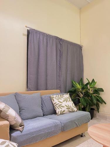 a blue couch in a living room with a window at V Lodge in Kuantan