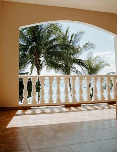 a white balcony with palm trees in the background at Wiona of Villa Paraiso / Beachfront Villa & Pool in Big Creek