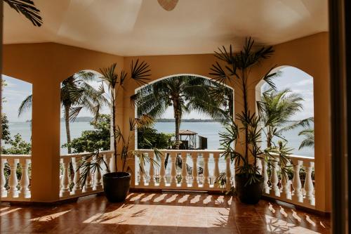 a room with a balcony with palm trees and the ocean at Wiona of Villa Paraiso / Beachfront Villa & Pool in Big Creek