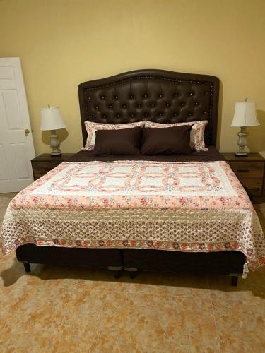 a bedroom with a large bed with two lamps at paradise cove in Spanish Town