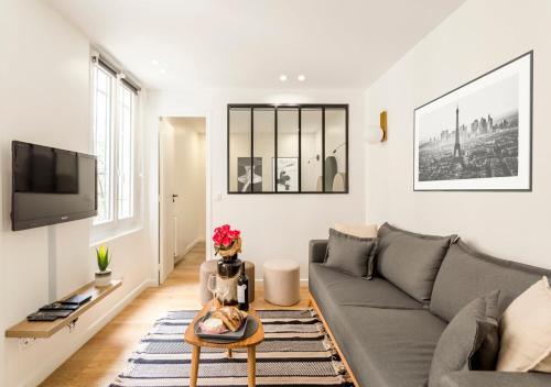 un salon avec un canapé et une télévision dans l'établissement Élégance & Design Paris Center, à Paris