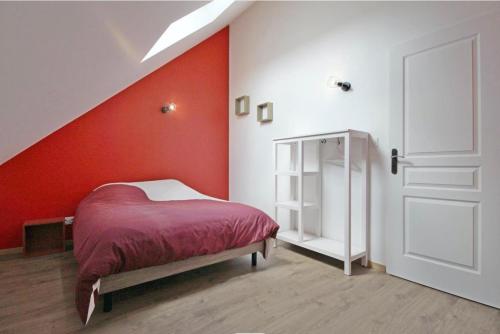 ein Schlafzimmer mit einem Bett und einer roten Wand in der Unterkunft Gîte de saint Calais in Conches-en-Ouche