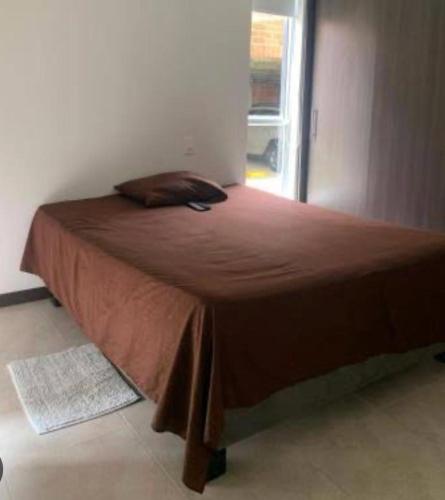 Una cama en un dormitorio con una manta marrón. en Departamento céntrico en Cajamarca, en Cajamarca
