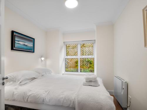 a white bedroom with a large bed and a window at Apartment 394 - Clifden in Clifden