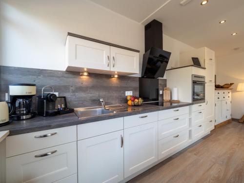a kitchen with white cabinets and a sink at Inselsünn Hotel und Apartments in Spiekeroog