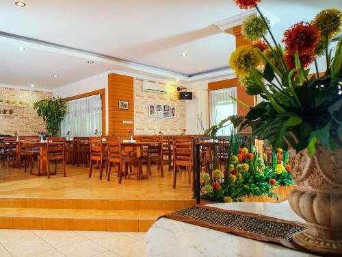 a restaurant with wooden tables and chairs and a vase of flowers at Capital O 142 Hotel Al Furqon Syariah in Palembang