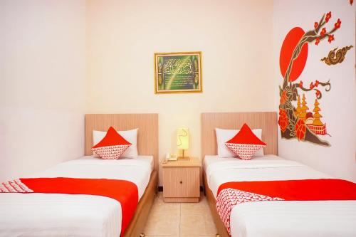 a room with two beds with red and white sheets at Capital O 142 Hotel Al Furqon Syariah in Palembang