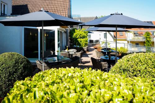 a patio with tables and chairs and umbrellas at Villa Bosco - Boutiquehotel in Walldorf
