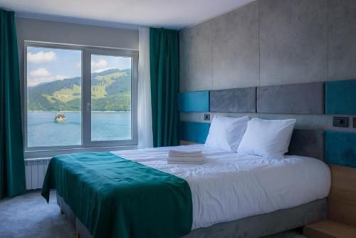 a bedroom with a large bed with a large window at Hotel Plutitor Lebăda in Bicaz