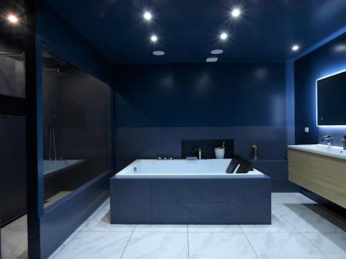 a blue bathroom with a bath tub and a tv at La Suite - Loft Spa in Tavernes