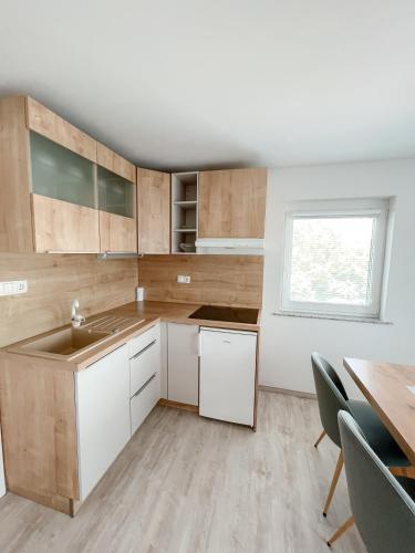 a kitchen with white cabinets and a table and a window at Apartments Sole in Podčetrtek