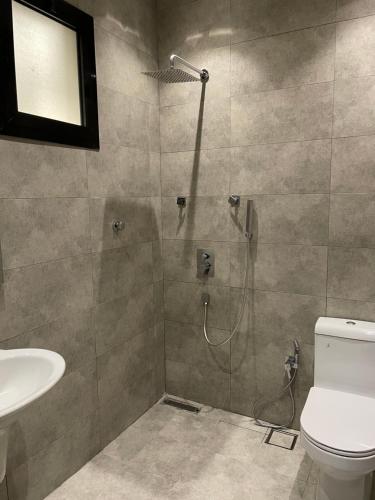 ein Bad mit einer Dusche, einem WC und einem Waschbecken in der Unterkunft أعناب الفندقية in Baljurashi