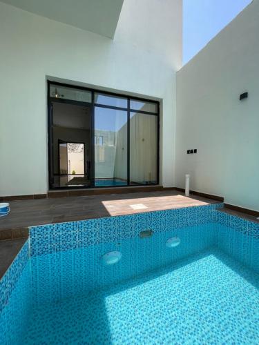 a swimming pool in a room with a blue tiled floor at أعناب الفندقية in Baljurashi
