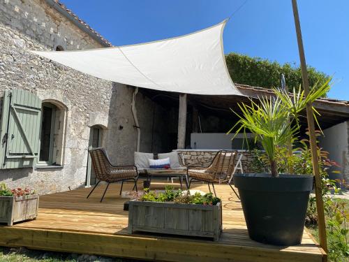 a wooden deck with chairs and a white umbrella at Figtrees in Margueron