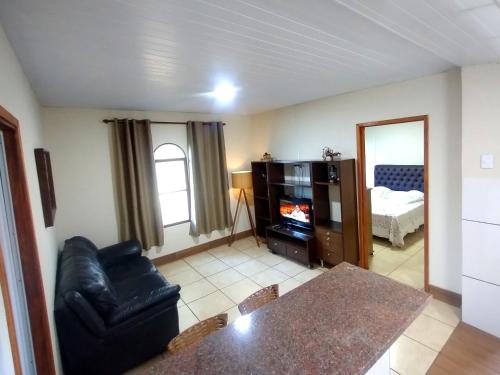 a living room with a black leather couch and a television at Villa Donn'Anna in Analândia