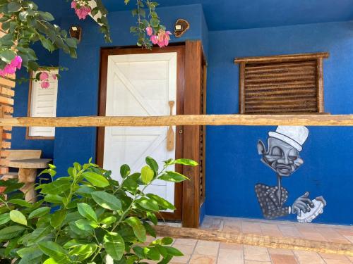 a blue house with a painting on the wall at Pousada Nascer da Lua in Fortim