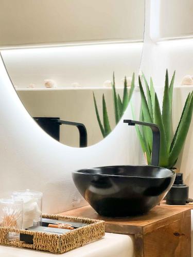 a black bowl on a table with a plant in front of a mirror at Gèa Athenian Suites in Athens