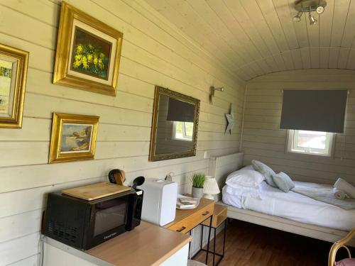 a small room with a bed and a television at Lakeside Shepard's Hut 'Sanderling' in Bishampton
