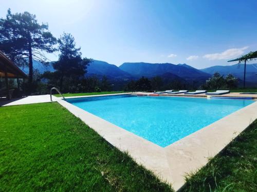 a swimming pool with chairs and mountains in the background at Villa Olymposzaray in Kumluca