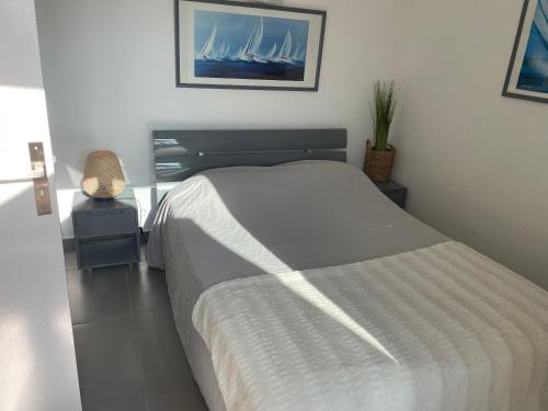 une chambre avec un lit et un tableau de navires dans l'établissement Magnifique appartement vue port et mer, au Cap d'Agde