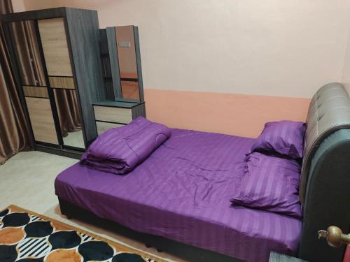 a bedroom with a bed with purple sheets and a mirror at Siti Homestay in Pasir Mas