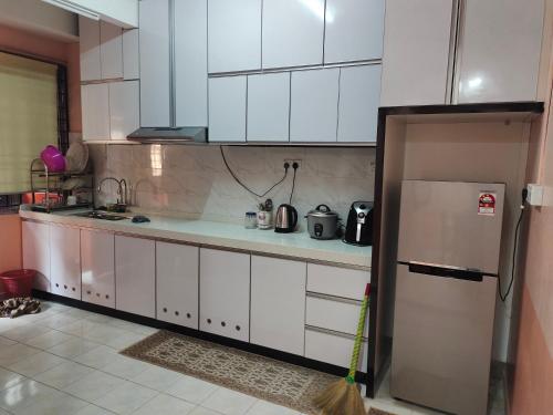 a kitchen with white cabinets and a refrigerator at Siti Homestay in Pasir Mas