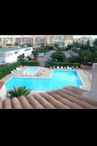 Elle offre une vue sur la grande piscine bordée de chaises. dans l'établissement Magnifique appartement vue port et mer, au Cap d'Agde