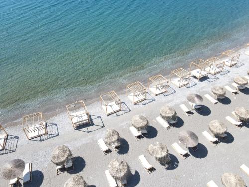 een uitzicht over een strand met stoelen en parasols bij Alia Luxury Suites and Spa in Charaki