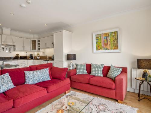 a living room with two red couches and a kitchen at Clifden Seaview - Stunning Apartment in Clifden