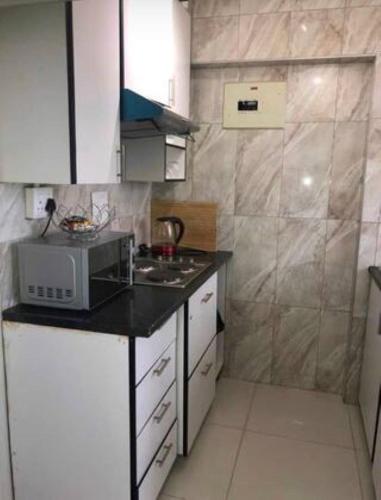 a small kitchen with a stove and a microwave at Elegant Durban Harbor View Bnb in Durban