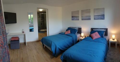 a bedroom with two beds with blue sheets and a tv at Havre champêtre, maison et chalet in Guerville