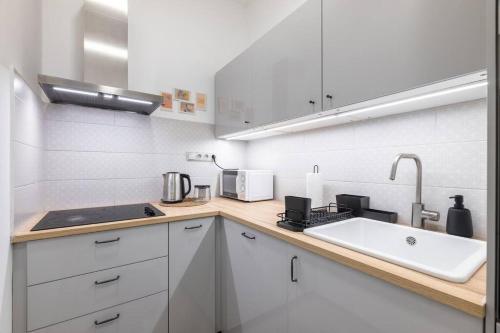 a white kitchen with a sink and a microwave at Cute 1bedroom center apartment in Prague