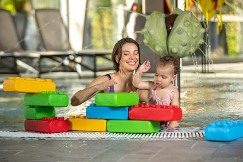 a woman and a baby playing in the water at Grand SPA Lietuva Serviced Apartments Dzūkija in Druskininkai