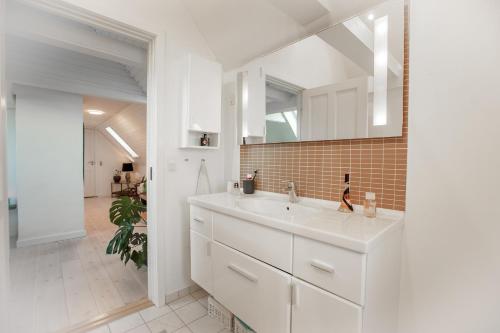 een witte badkamer met een wastafel en een spiegel bij Lindebjerggårds Bed and Breakfast in Melby