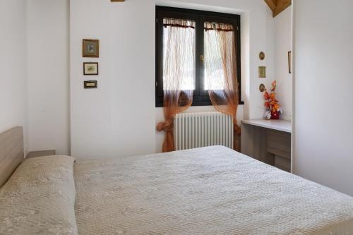 a white bedroom with a bed and a window at Appartamento Gaia in Caspoggio