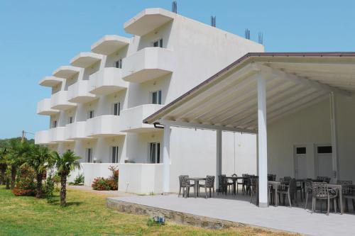 a large white building with tables and chairs at Hotel Velipoja Village in Velipojë