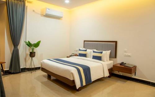 a bedroom with a large bed with blue and white pillows at The Fortune Hotel By Swathi Group in Koppal
