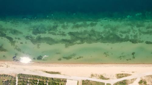 eine Luftansicht auf einen Strand mit grünem Wasser in der Unterkunft Sun Beach Hotel in Agía Triás