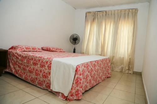 a bedroom with a bed with a red blanket and a window at Sakura Hill in Kandy