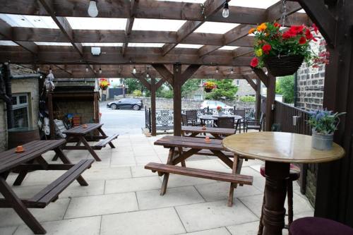 a patio with wooden benches and a table with flowers at The New Rushcart Inn & Country Dining in Sowerby Bridge