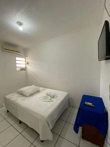 a white room with a bed and a blue stool at Pousada o Paraiso in Camamu