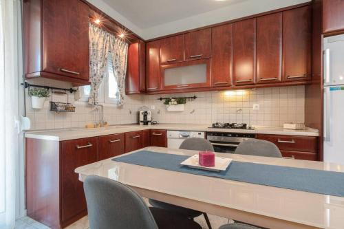 a kitchen with wooden cabinets and a table with chairs at Tommy's Family Apartment in Katerini
