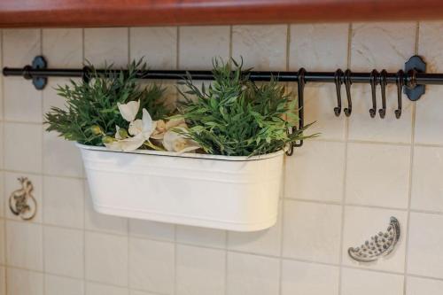 a white pot with plants on a wall at Tommy's Family Apartment in Katerini